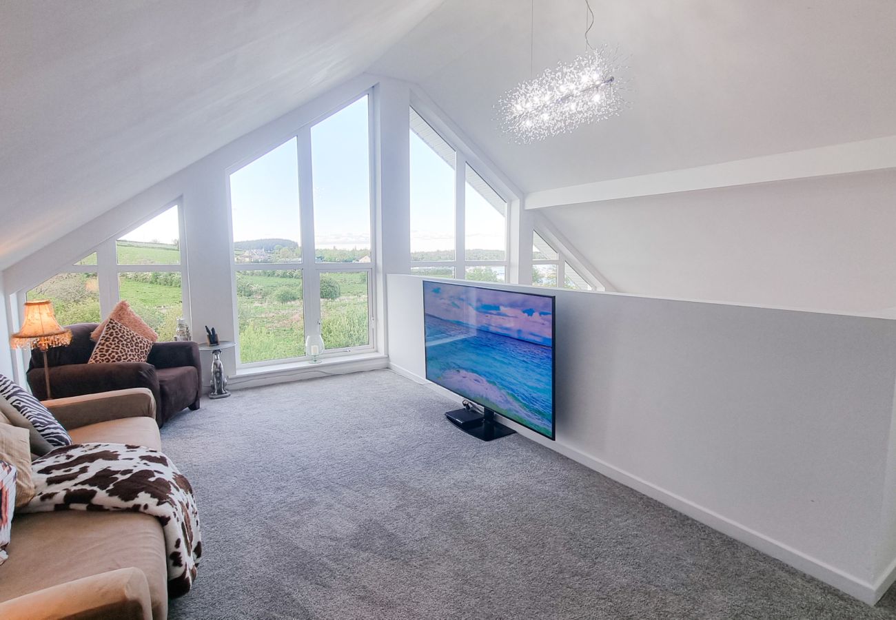 Riverrun Holiday Home No 15.  Mezzanine area, couch and TV large windows with view to garden. 