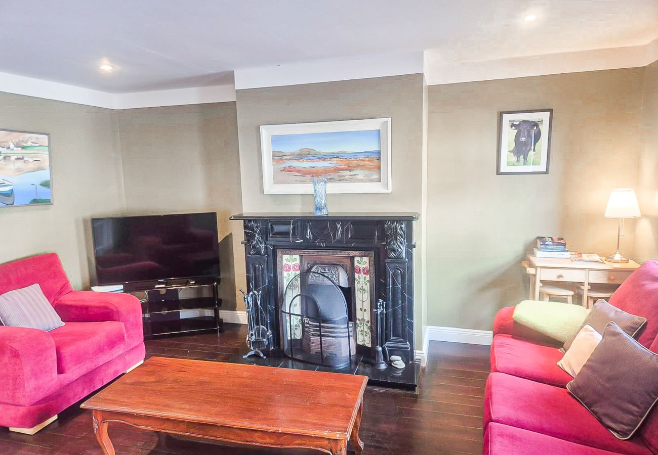 Dingle Town Holiday Home. Comfortable colourful seating, open fire.