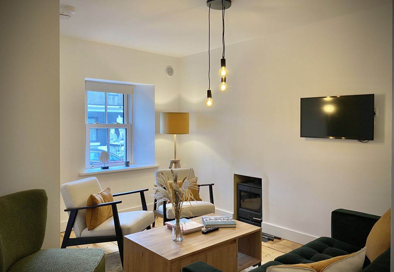 Clifden Town Townhouse. Connemara. Open plan lounge with comfortable sofa, wooden floors, TV. Contemporary lighting, modern furniture. View to the squ