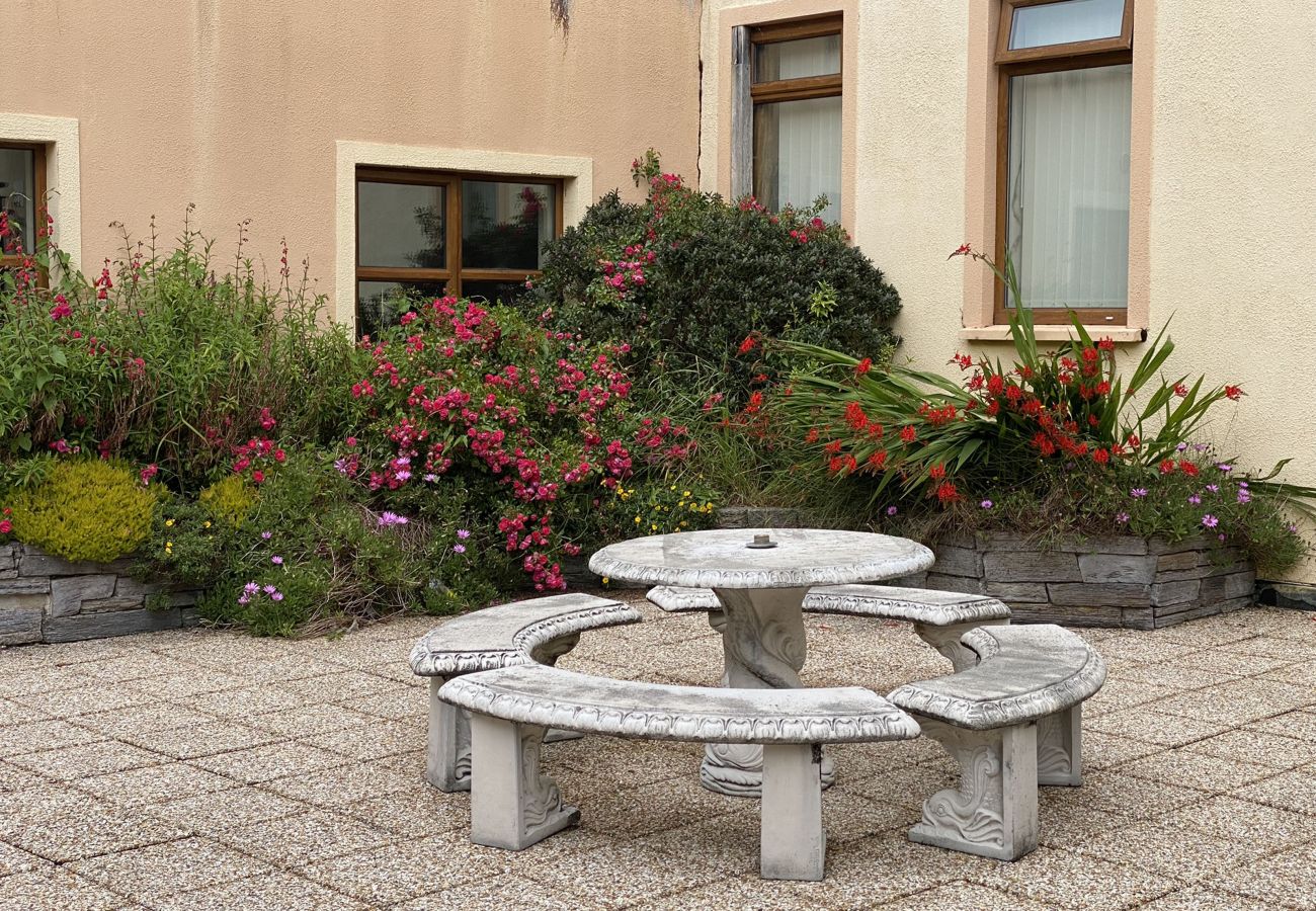 Clifden Town Holiday Apartment. Courtyard, stylish seating area, flowers. 