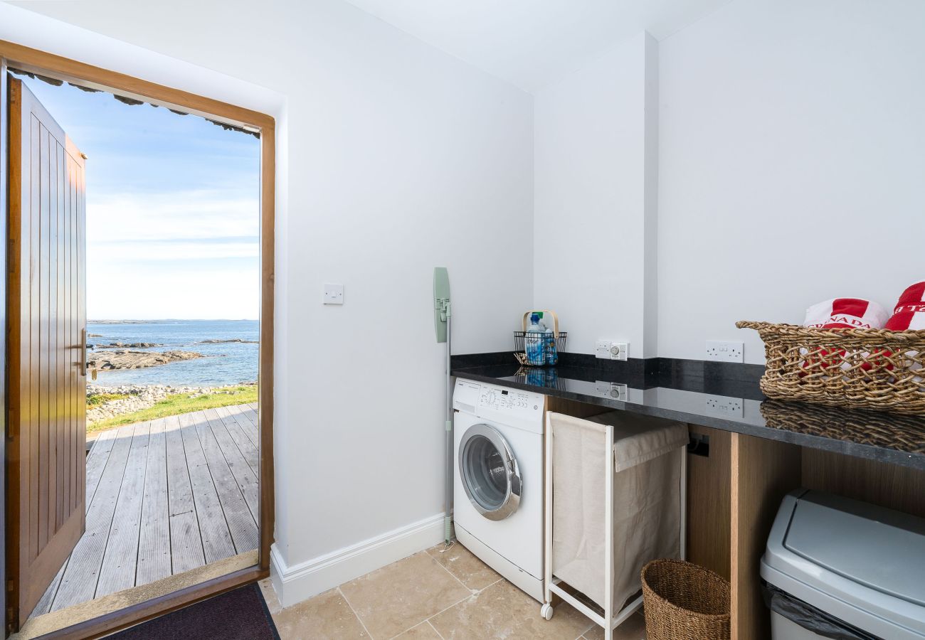 Ocean View Holiday Home. Utility room with washing machine. Access to decking with view to the sea.