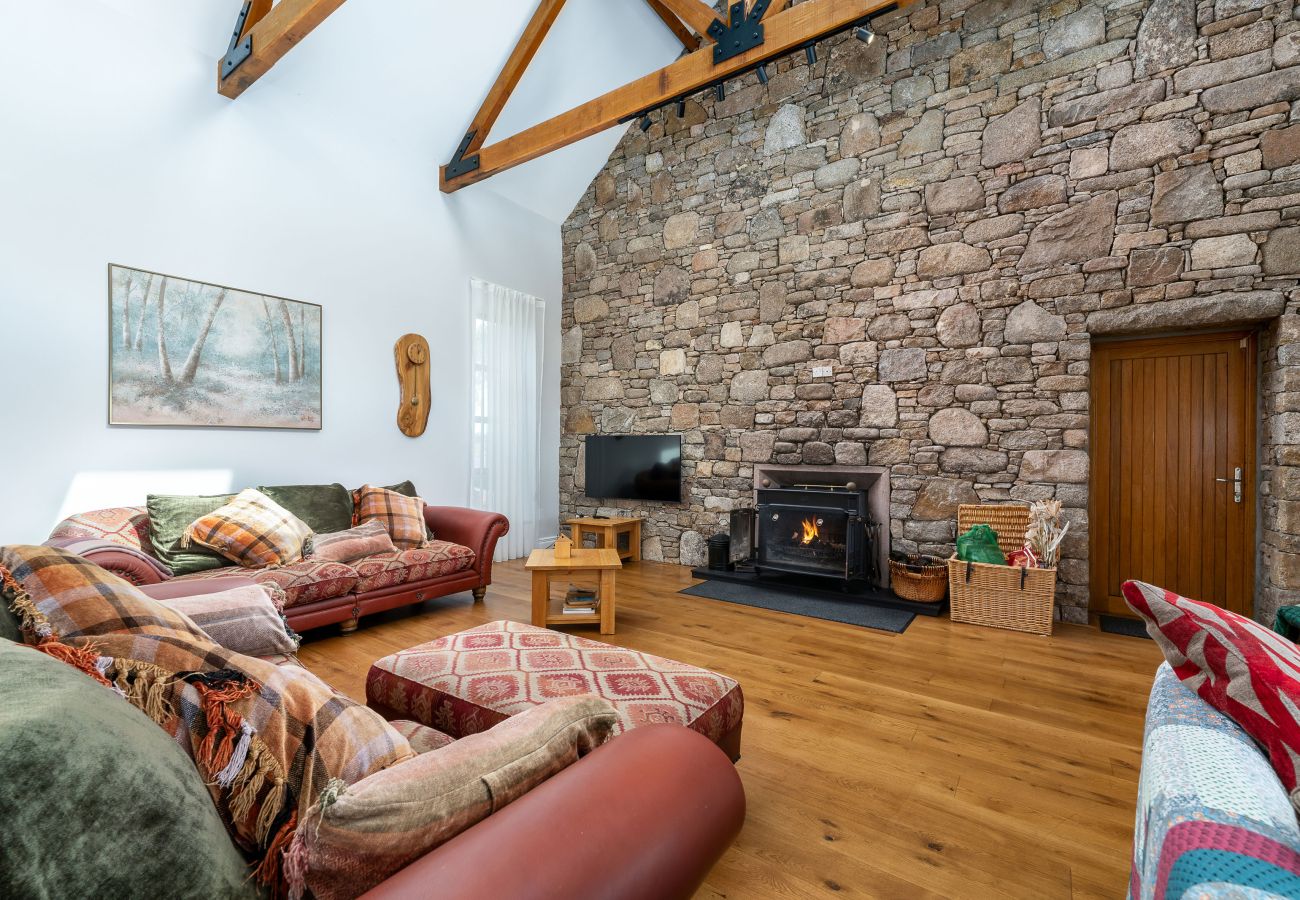 Ocean View Holiday Home. Living room, open fire, stone wall, comfortable stylish furniture. 