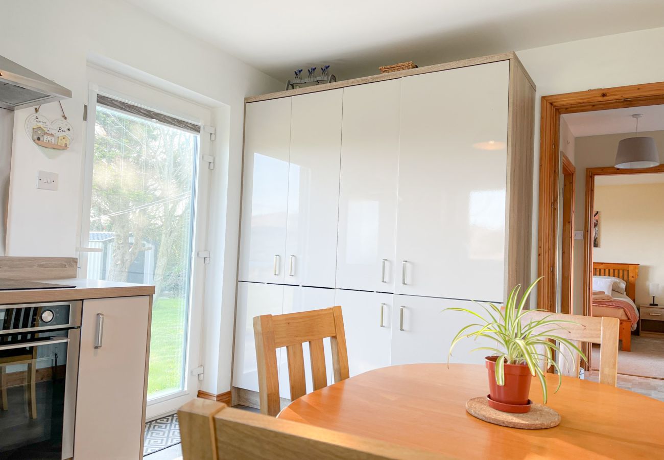 Honeybee Cottage Valentia Co Kerry. Dining table with four chairs, view to garden. 