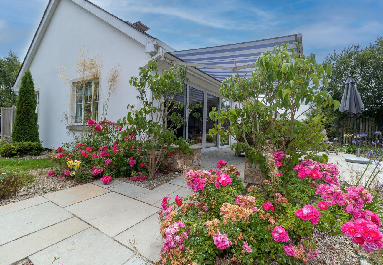 Brittas Bay Holiday Park No. 7. Paved patio with awning and garden furniture. Mature bright floral garden. 