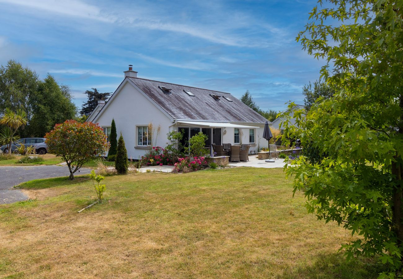 Brittas Bay Holiday Park No. 7. Exterior back garden with patio and wicker furniture. Mature trees and flowers. 