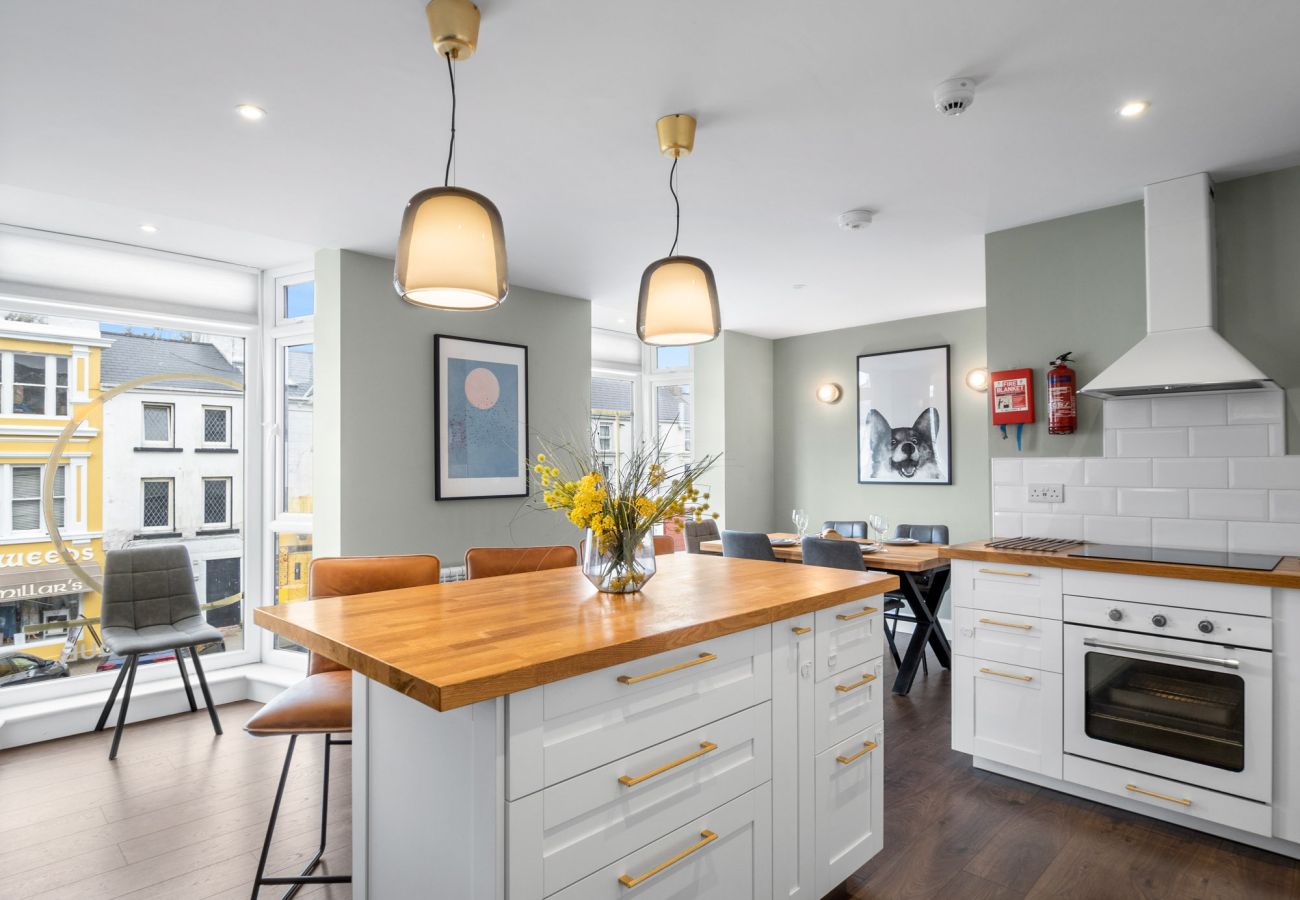 Clifden Boutique Apartment. Open plan kitchen diner, island, wooden floors large window.