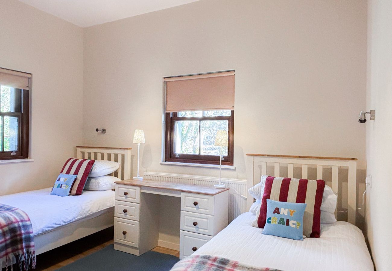 Kylemore Woodland Holiday Cottage, twin beds with window and dresser. 