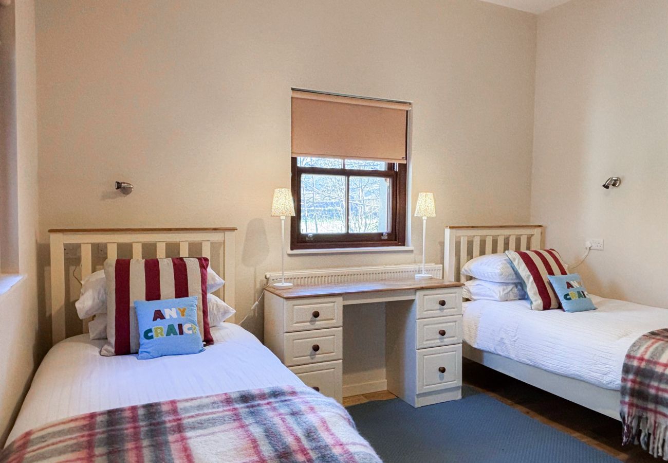 Kylemore Woodland Holiday Cottage, twin beds with window and dresser. 
