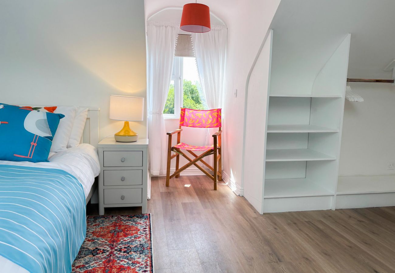 Luxurious Clifden Cottage. Twin room with bright colours and wooden floor. Seating in window
