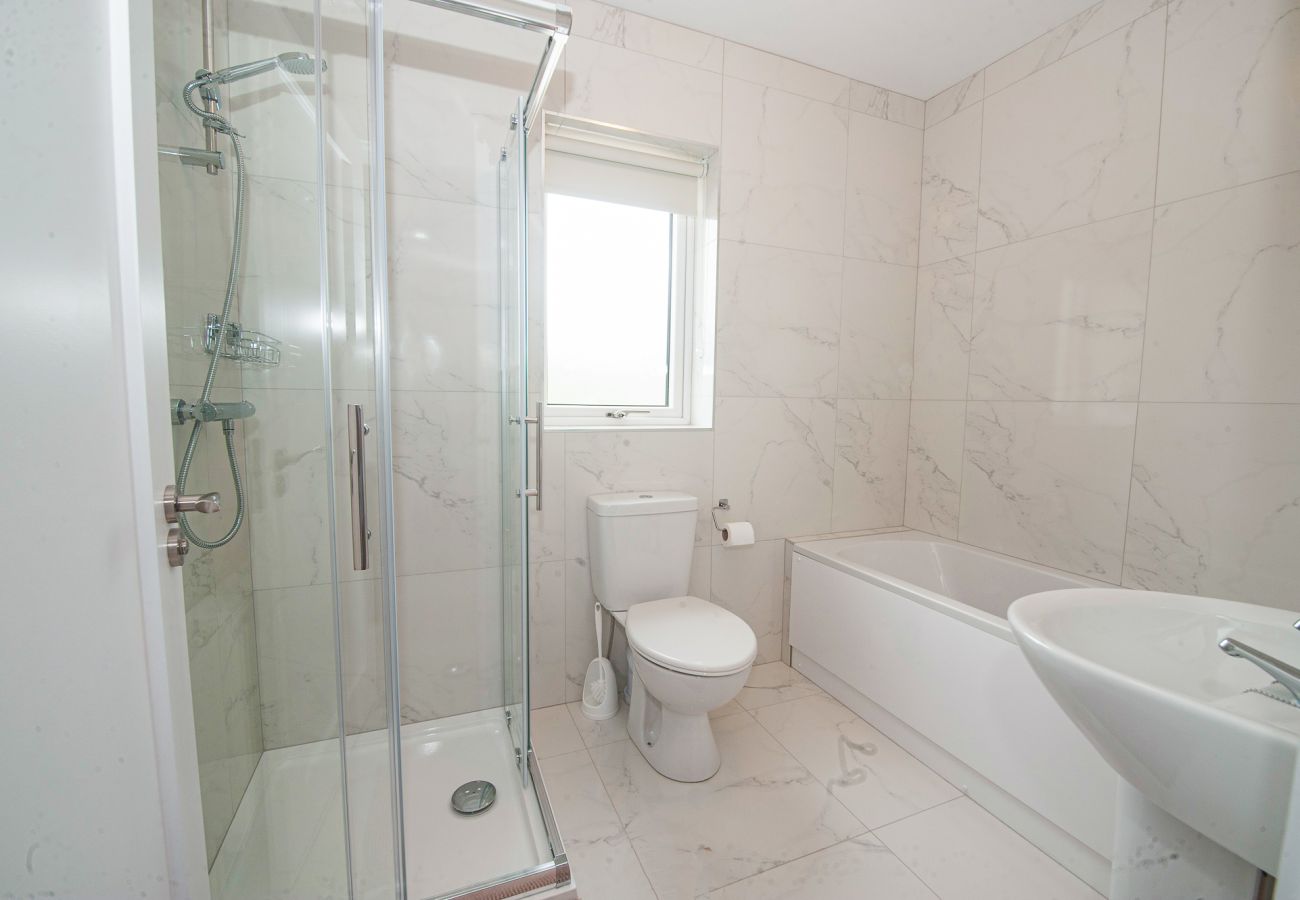Dunmore East Sunrise Meadows Holiday Home. Bathroom with bath, shower, sink and WC. Bright, white contemporary tiling. 